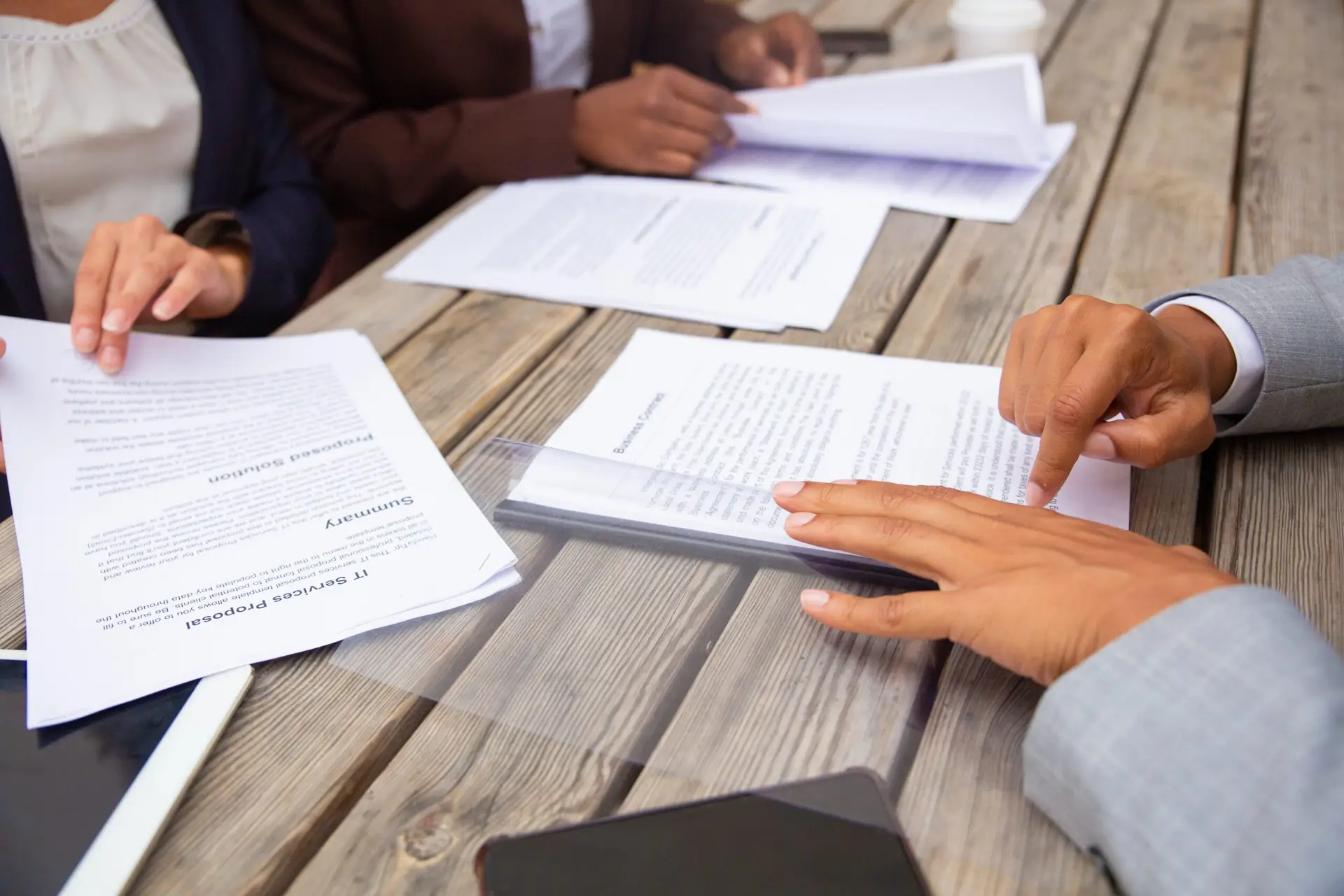 Business people studying contract terms at meeting. Business man and women sitting at cafe table and reading documents.